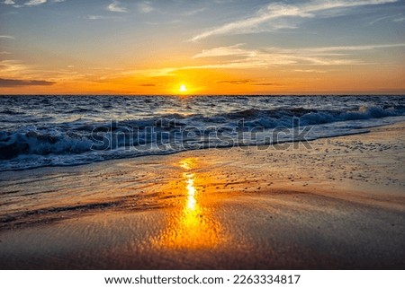 Colorful vibrant orange sunset seascape in Gulf of Mexico in Seaside Santa Rosa Beach, Florida panhandle and reflection of sun path on horizon