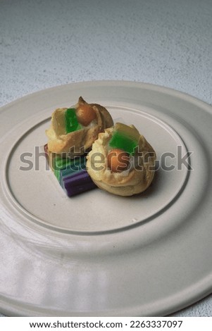 eclairs with fruit and jelly topping on a plate.