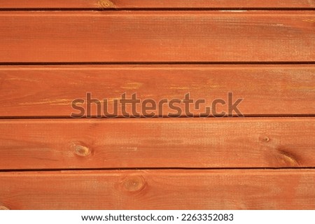 The wall is made of wooden clapboard painted with water-repellent rowan-colored paint.Natural wooden background made of boards.The facade of a country house.