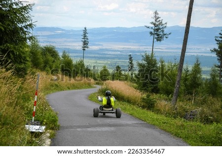 Back view of girl riding around a go cart track in mountain cart above Tatranska Lomnica, High Tatras, Slovakia Royalty-Free Stock Photo #2263356467