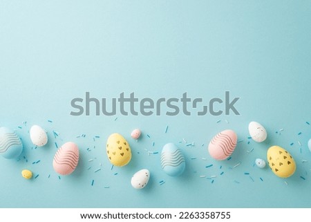 Easter concept. Top view photo of colorful easter eggs in row and sprinkles on isolated pastel blue background with copyspace
