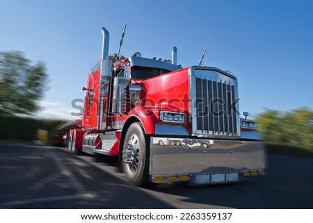 Front view of red classic bonnet American big rig semi truck tractor with awesome stylish chrome accessories standing on truck stop with flat bed semi trailer caring covered commercial cargo  Royalty-Free Stock Photo #2263359137