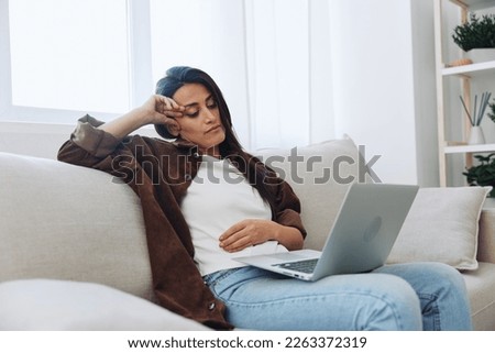 Woman freelancer on day off sitting on sofa with laptop at home online video chat call, smile