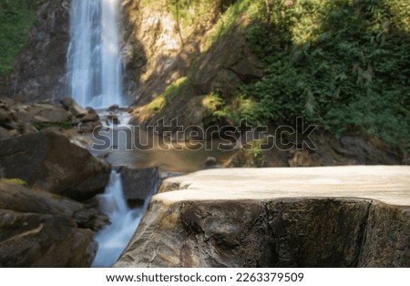 wood table top podium in outdoors waterfall green lush tropical forest nature background.organic healthy natural product present placement pedestal counter display,website banner cover jungle concept.