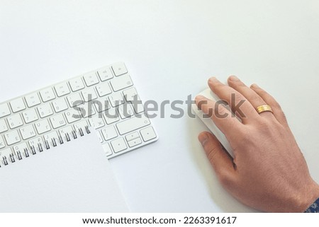 Man holding computer mouse with notepad on table