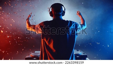 Rear view of cool dj performing in a nightclub, dancing at mixer controller and cheering the crowd up - nightlife concept  Royalty-Free Stock Photo #2263398159