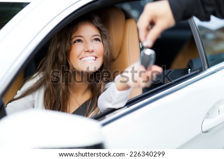 Young woman receiving the keys of her new car Royalty-Free Stock Photo #226340299