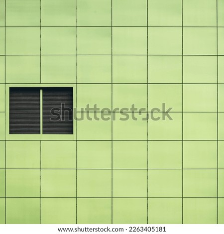 Minimalist background with beautiful smooth greenish square tiles close-up. Light green texture of outside wall closely. Minimal backdrop with easy green sleek facing tile of office building side.