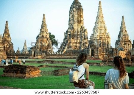 Two young women tourists stand to admire the beauty of Wat Chaiwatthanaram, Thailand.