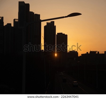 Under the orange-colored sky, it is a picture of the silhouette of the city center at sunset.