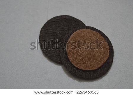 selective focus, cookie consisting of two chocolate wafers with chocolate cream filling on a rough white tissue background