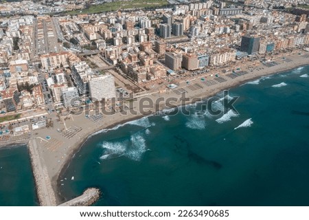 Aerial drone photo of the beautiful beach front of the coastal town of  Fuengirola in Malaga Spain Costa Del Sol, showing the sandy beach, hotels and apartments with the mountains in the background
