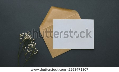 Postal envelope and a blank sheet on a dark background. Gypsophila flowers and a letter with space for text