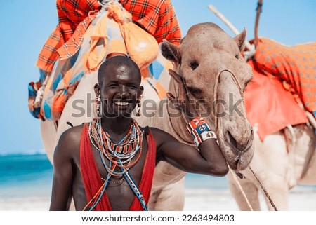 Maasai warrior with a camel, entertainment for tourists on the beach in Kenya Royalty-Free Stock Photo #2263494803