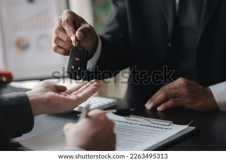 A car rental company employee pointed out the renter to sign the rental agreement after discussing the details and rental terms with the renter. Concept of car rental.