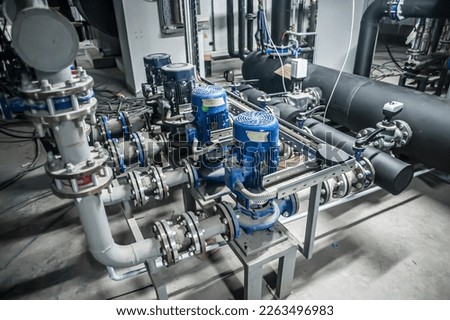 Huge industrial water pump and air handling unit in the ventilation plant room with ductworks and insulated pipelines Royalty-Free Stock Photo #2263496983