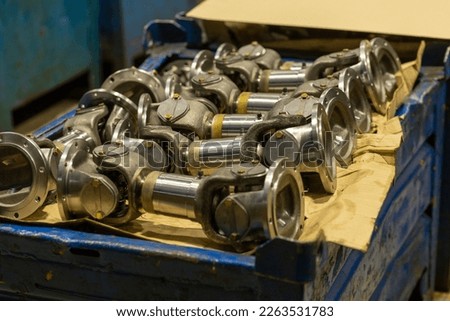 Cardan shafts and gimbal transmissions laying in box during production process. Production of automotive components for trucks and agricultural machinery.