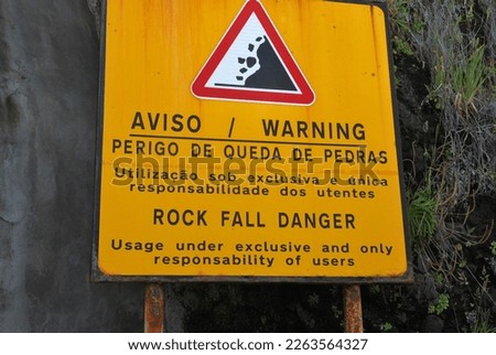 A sign warning about rock fall danger in Portuguese and English. Saying: 'usage under exclusive and only responsibility of users'