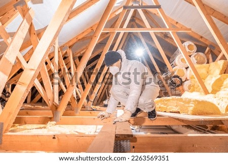 man insulates the roof and ceiling of the house with glass wool Royalty-Free Stock Photo #2263569351