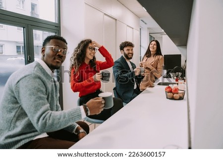 A photo of junior multiracial coworkers enjoying their coffees at the office kitchen. Working in a good atmosphere