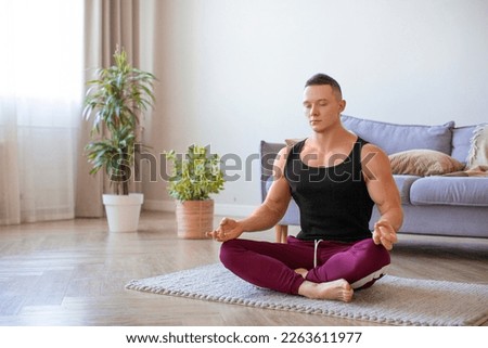 Young fit man practicing yoga at home. Meditation and calmness. Healthy lifestyle concept.