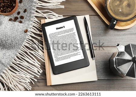 Flat lay composition with portable e-book reader and notebook on wooden table Royalty-Free Stock Photo #2263613111