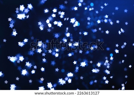 Many beautiful shimmering stars and blurred lights on dark blue background. Bokeh effect