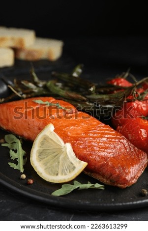 Delicious cooked salmon with lemon on black table, closeup. Healthy meals from air fryer