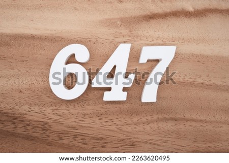 White number 647 on a brown and light brown wooden background.