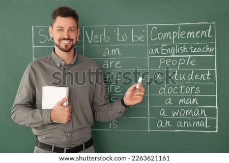 Happy teacher with book explaining English at blackboard