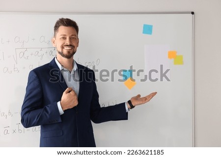 Happy teacher explaining mathematics at whiteboard in classroom Royalty-Free Stock Photo #2263621185
