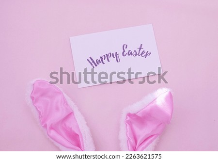 Easter bunny ears on a pink background.  Postcard with text Happy Easter.