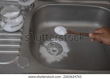 Man pouring baking soda to clear clogs in sinks and drains at home Royalty-Free Stock Photo #2263624761
