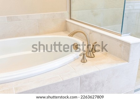 Modern white plain clean bathroom and closeup of bathtub with shower and tiles in model staging house, home or apartment