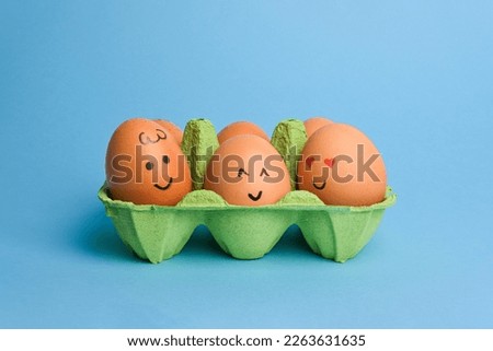 Cute easter eggs with funny faces in green box isolated on blue background. Happy easter concept.