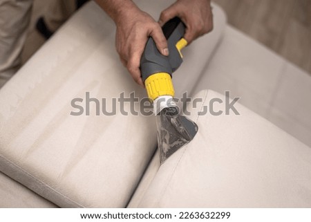 Cleaning a dirty sofa with a sofa washer. Close up of hands holding sofa cleaner. Professional sofa wash. Upholstery wash image Royalty-Free Stock Photo #2263632299