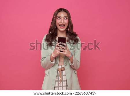 Happy Asian woman using mobile phone isolated on pink studio background.