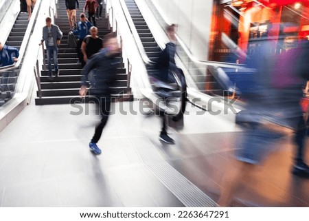 picture with motion blur effect of people rushing down an escalator to a subway station