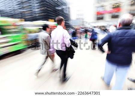 picture with camera made motion blur effect of business men walking on a busy city street