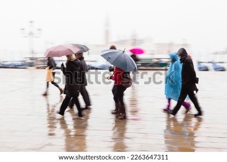 picture with camera made motion blur effect of people with umbrellas walking on a rainy day in Venice, Italy