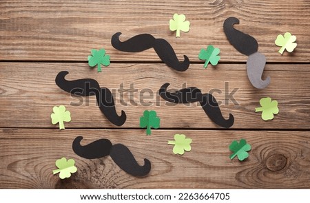 St.Patrick 's Day. Paper-cut mustache with clover leaves on a wooden table. Top view. Flat lay