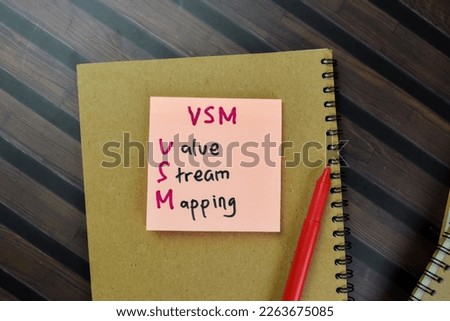 Concept of VSM - Value Stream Mapping write on sticky notes isolated on Wooden Table.