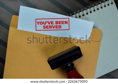 Concept of Red Handle Rubber Stamper and You've been Served text above from brown envelope isolated on on Wooden Table. Royalty-Free Stock Photo #2263675093