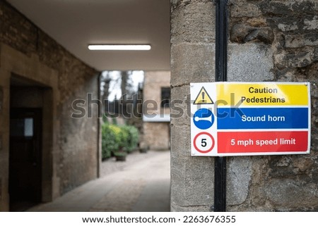 Shallow focus of a traffic warning sign. Due to the narrow gap, vehicles must take caution. Seen at an entrance to a public school in England.