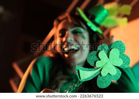 Joyful woman in background celebrating Saint Patrick's Day with a clover in foreground
