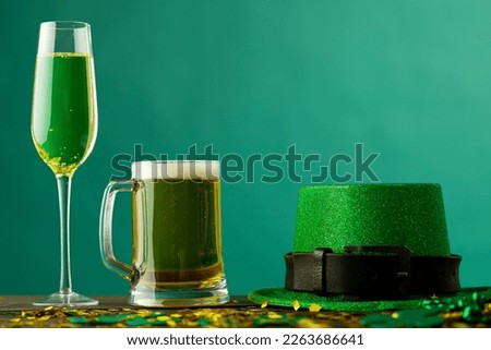 Image of beer and champagne glasses, green hat and copy space on green background. St patrick's day, irish tradition and celebration concept.