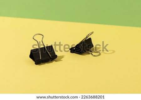 Black binder clips on a yellow background.