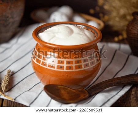 homemade or farm sour cream in earthenware jug on rustic background Royalty-Free Stock Photo #2263689531