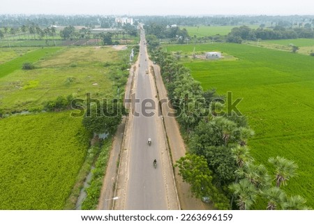 Aerial view of rural road passing through paddy fields near Tenali town, Guntur district, Andhra Pradesh state in India. Royalty-Free Stock Photo #2263696159