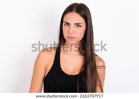 young woman wearing sportswear over white studio background frowning his eyebrows being displeased with something.